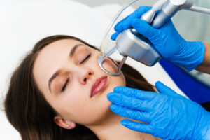 Process of facial CO2 laser resurfacing. Cosmetologist removes wrinkles and scars using laser from face of attractive girl.